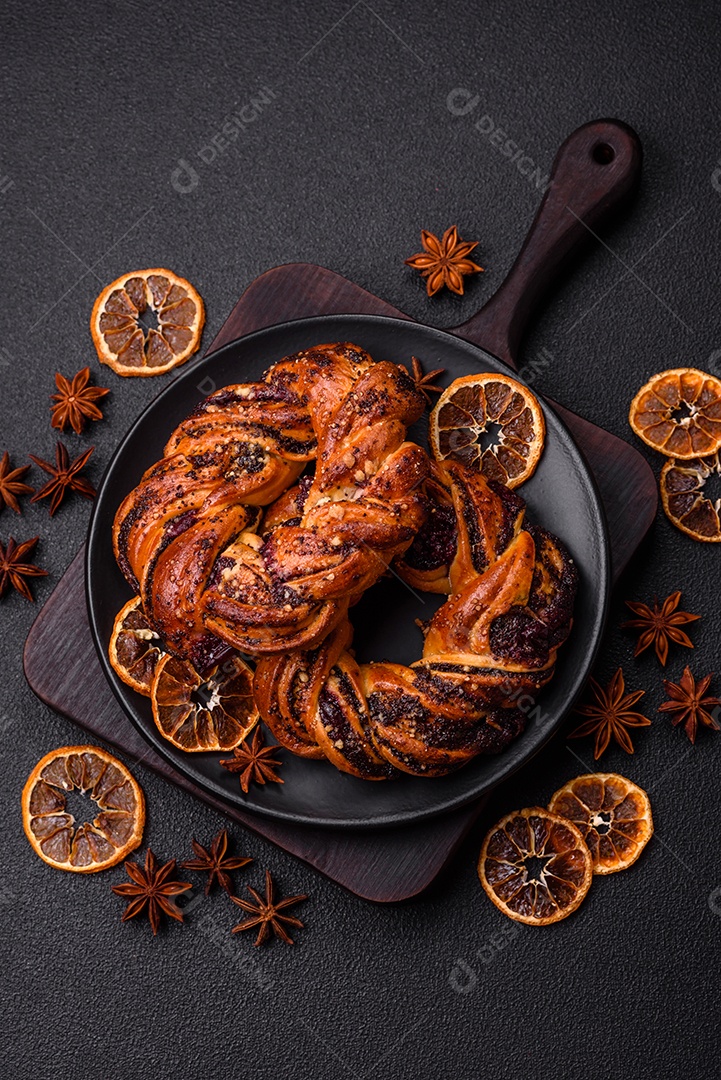 Delicioso pão fresco com sementes de papoila e bagas em forma de anel sobre um fundo escuro de concreto