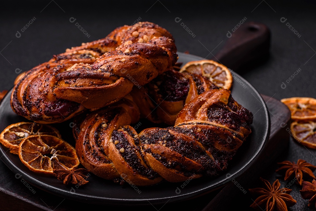 Delicioso pão fresco com sementes de papoila e bagas em forma de anel sobre um fundo escuro de concreto