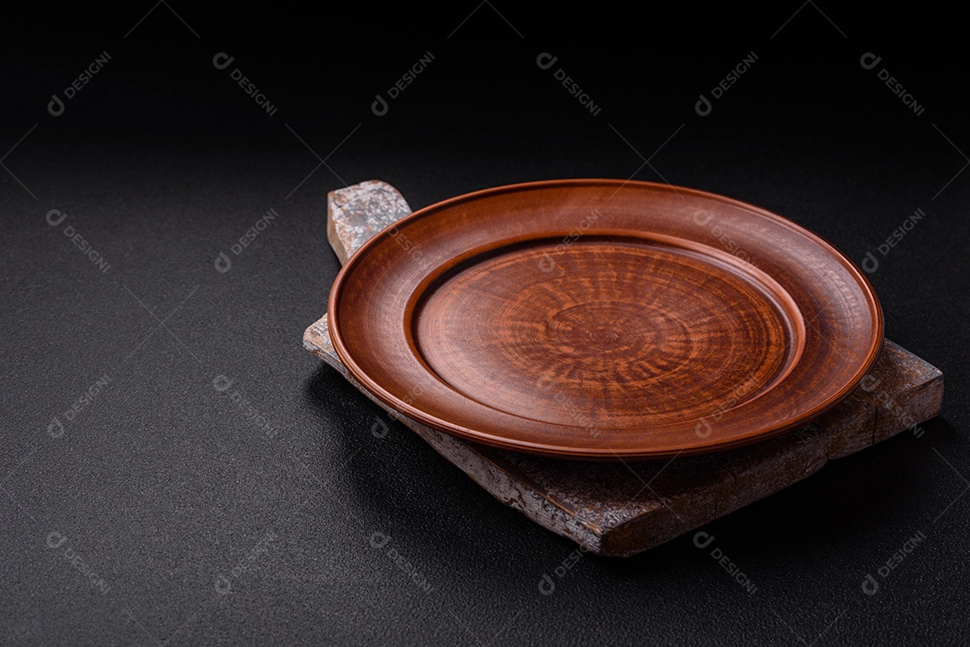 Placa redonda de cerâmica vazia em fundo de concreto texturizado escuro. Talheres, preparação para o jantar