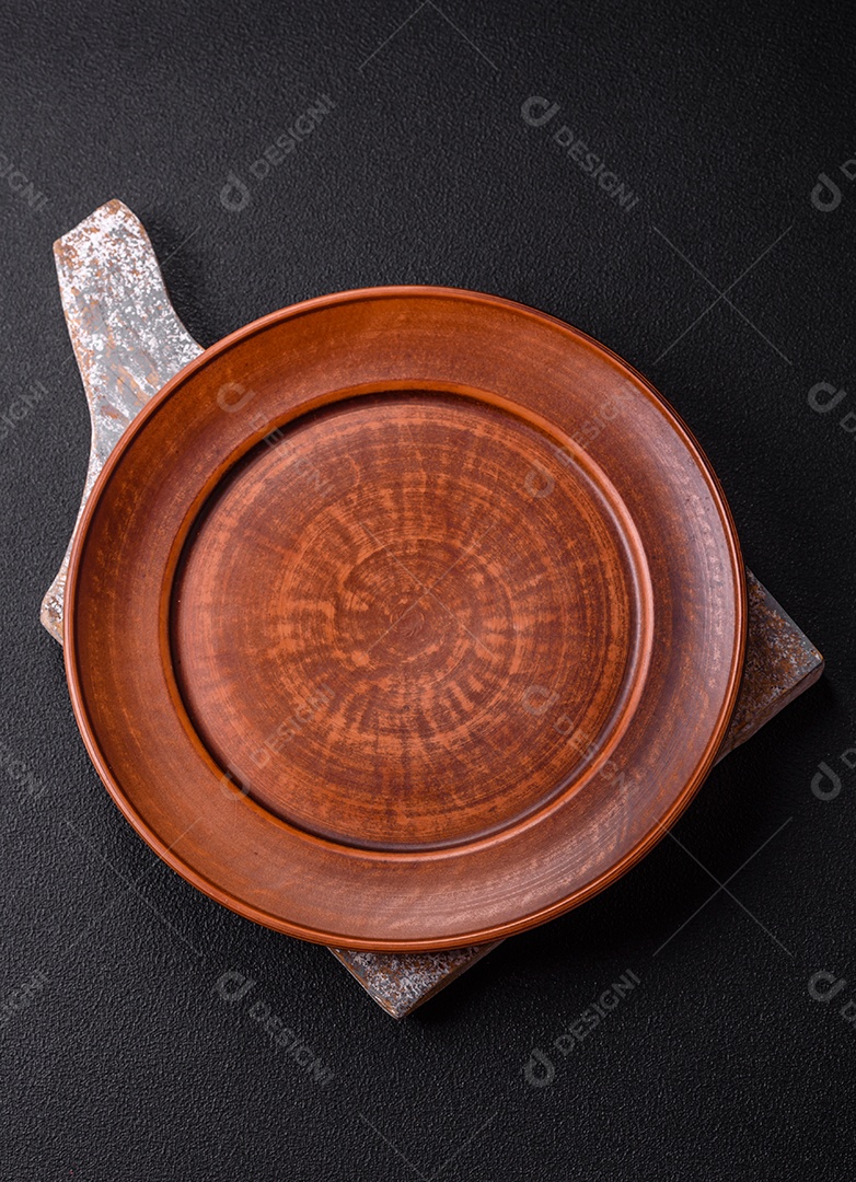 Placa redonda de cerâmica vazia em fundo de concreto texturizado escuro. Talheres, preparação para o jantar