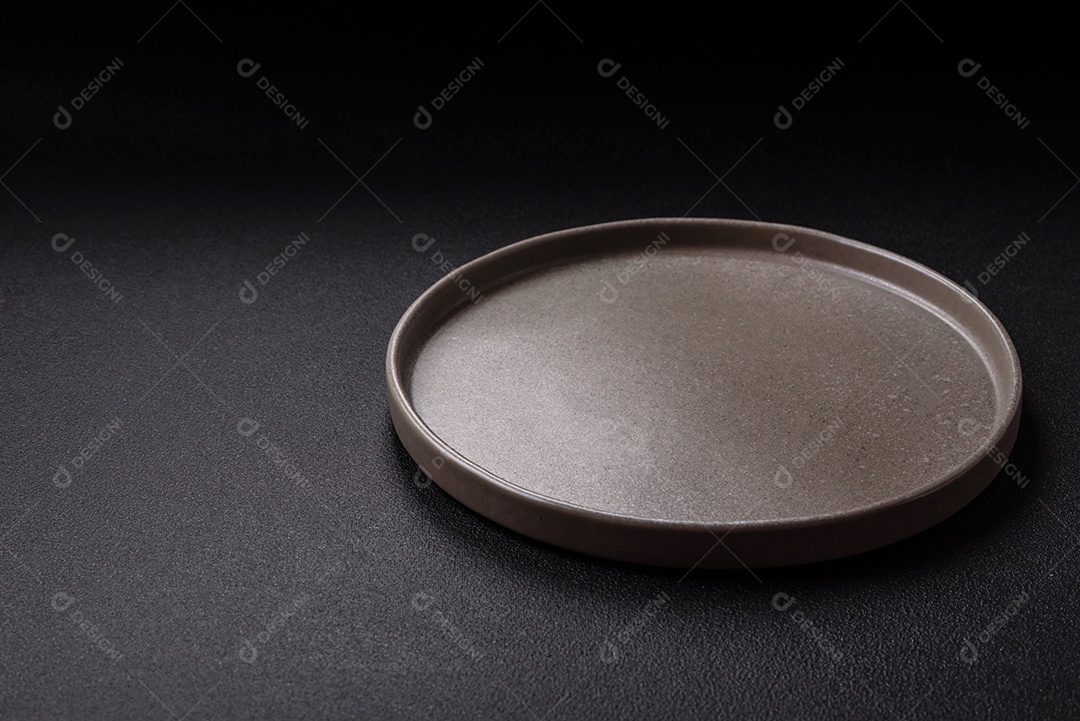 Placa redonda de cerâmica vazia em fundo de concreto texturizado escuro. Talheres, preparação para o