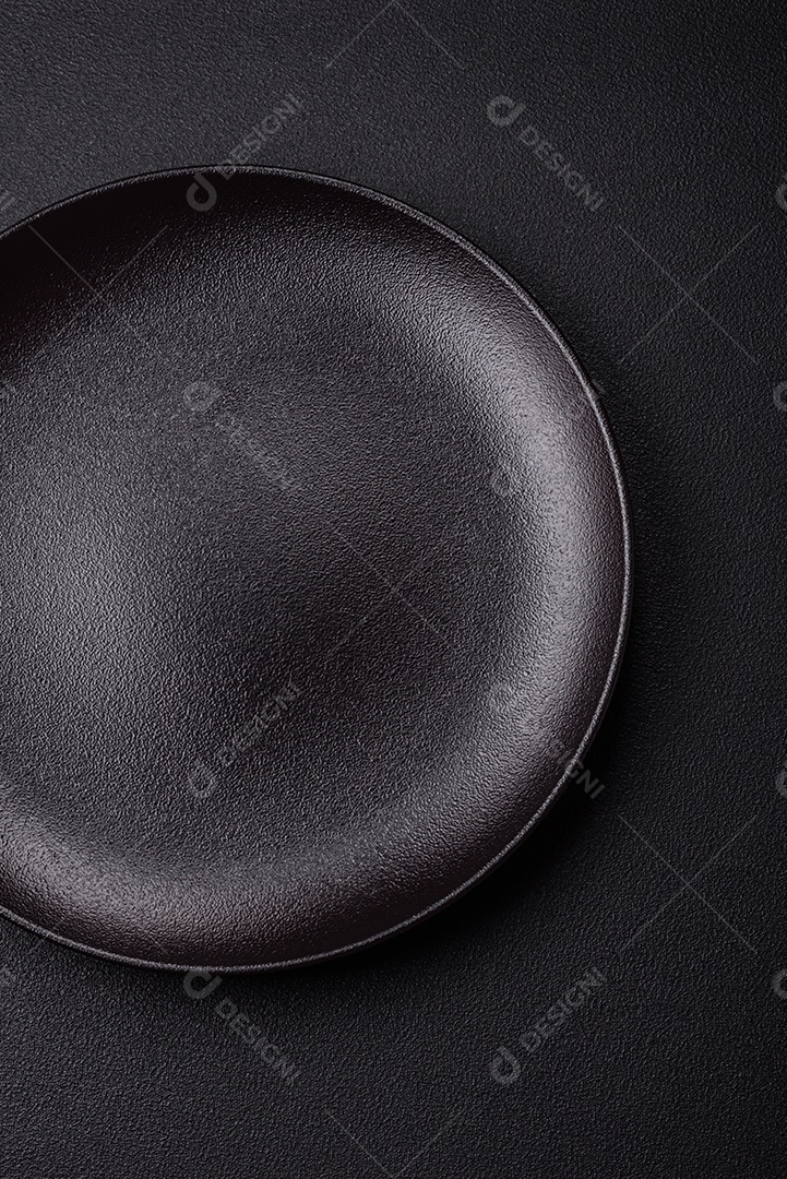 Placa redonda de cerâmica vazia em fundo de concreto texturizado escuro. Talheres, preparação para o jantar