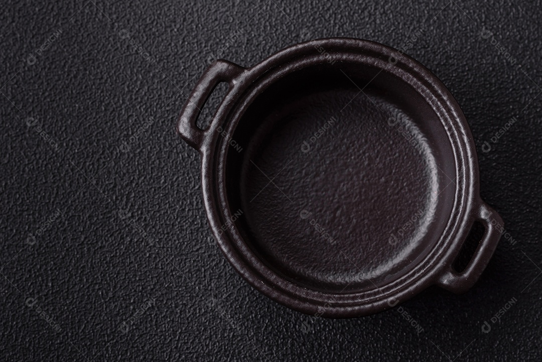 Placa redonda de cerâmica vazia em fundo de concreto texturizado escuro. Talheres, preparação para o jantar