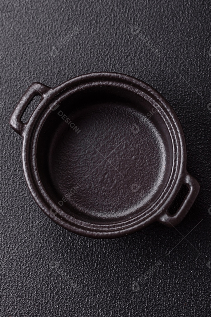 Placa redonda de cerâmica vazia em fundo de concreto texturizado escuro. Talheres, preparação para o jantar