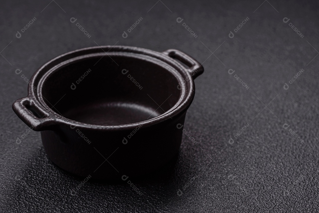 Placa redonda de cerâmica vazia em fundo de concreto texturizado escuro. Talheres, preparação para o jantar