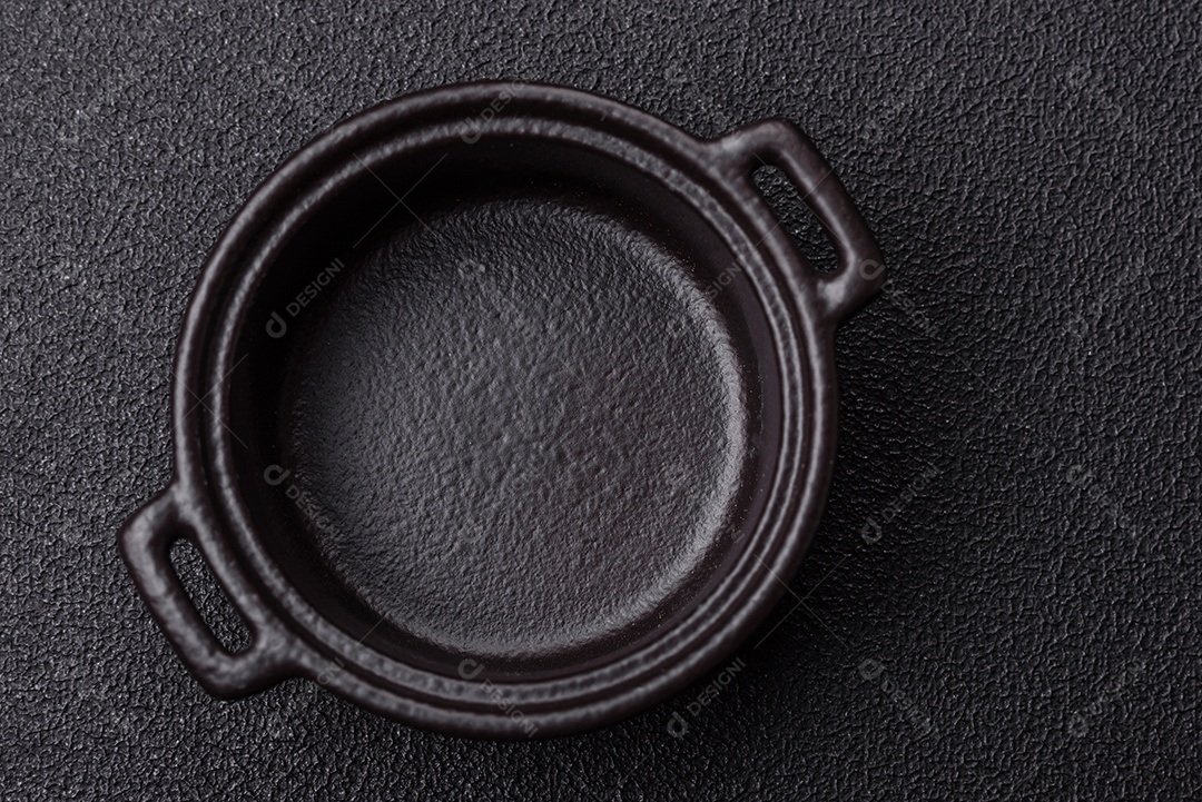 Placa redonda de cerâmica vazia em fundo de concreto texturizado escuro. Talheres, preparação para o jantar