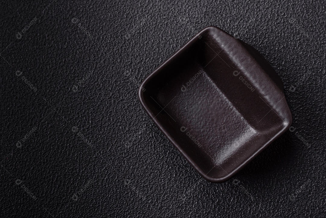 Placa redonda de cerâmica vazia em fundo de concreto texturizado escuro. Talheres, preparação para o jantar