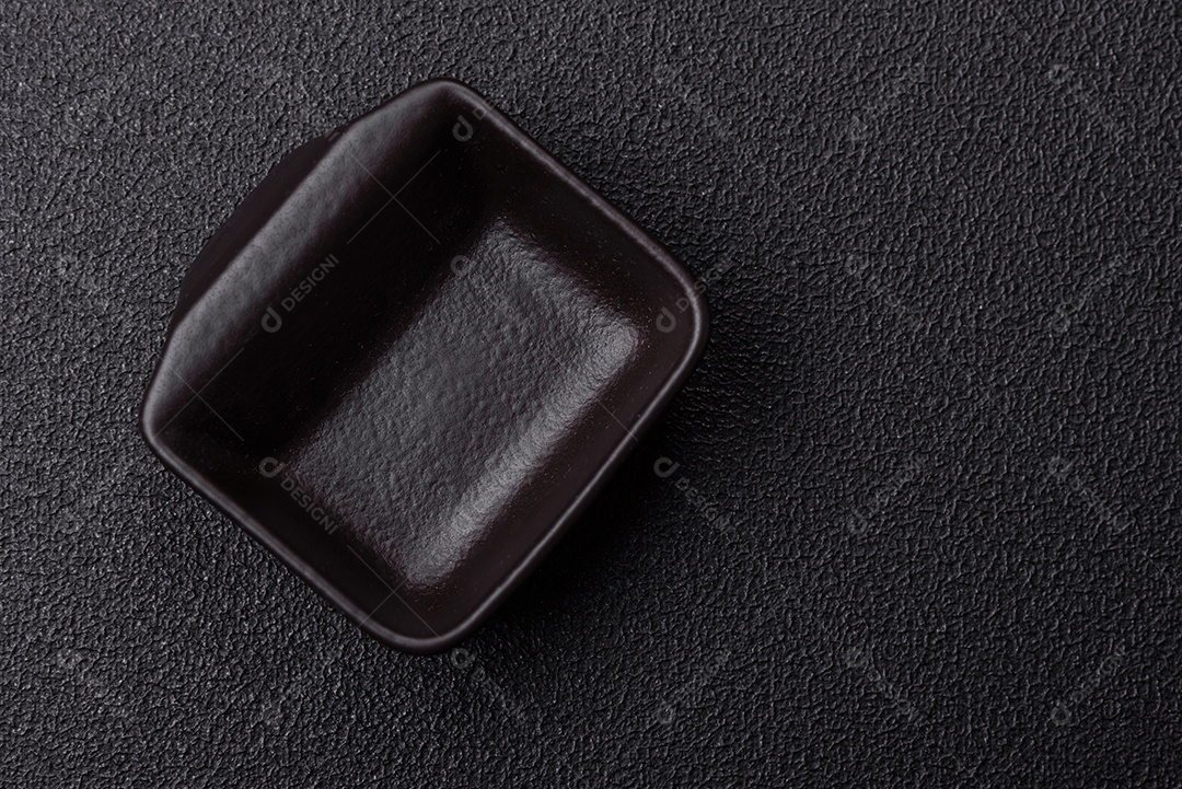 Placa redonda de cerâmica vazia em fundo de concreto texturizado escuro. Talheres, preparação para o jantar