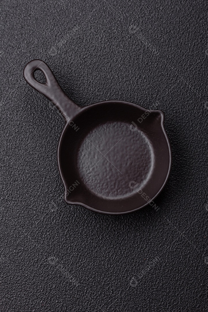 Placa redonda de cerâmica vazia em fundo de concreto texturizado escuro. Talheres, preparação para o jantar