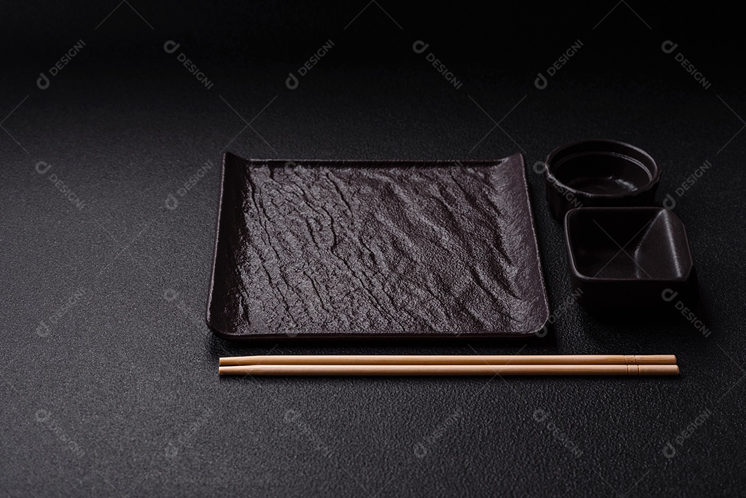 Placa redonda de cerâmica vazia em fundo de concreto texturizado escuro. Talheres, preparação para o jantar