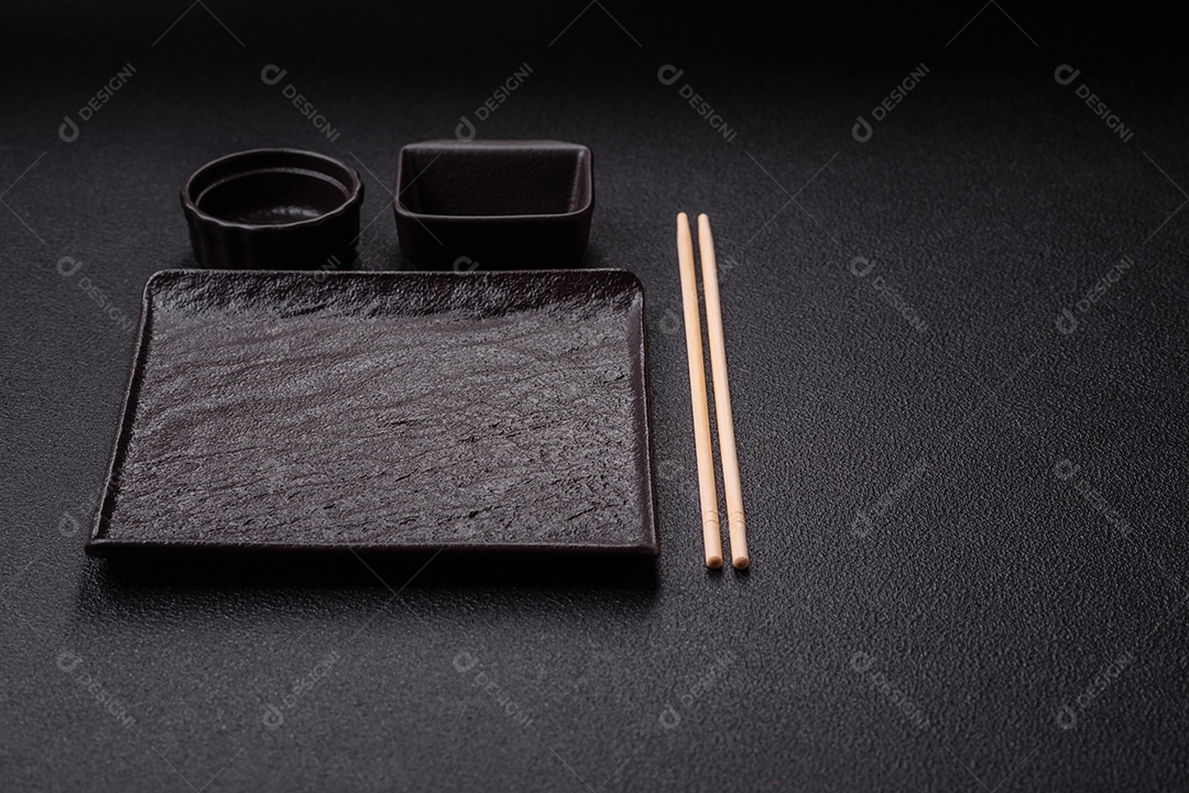 Placa redonda de cerâmica vazia em fundo de concreto texturizado escuro. Talheres, preparação para o jantar