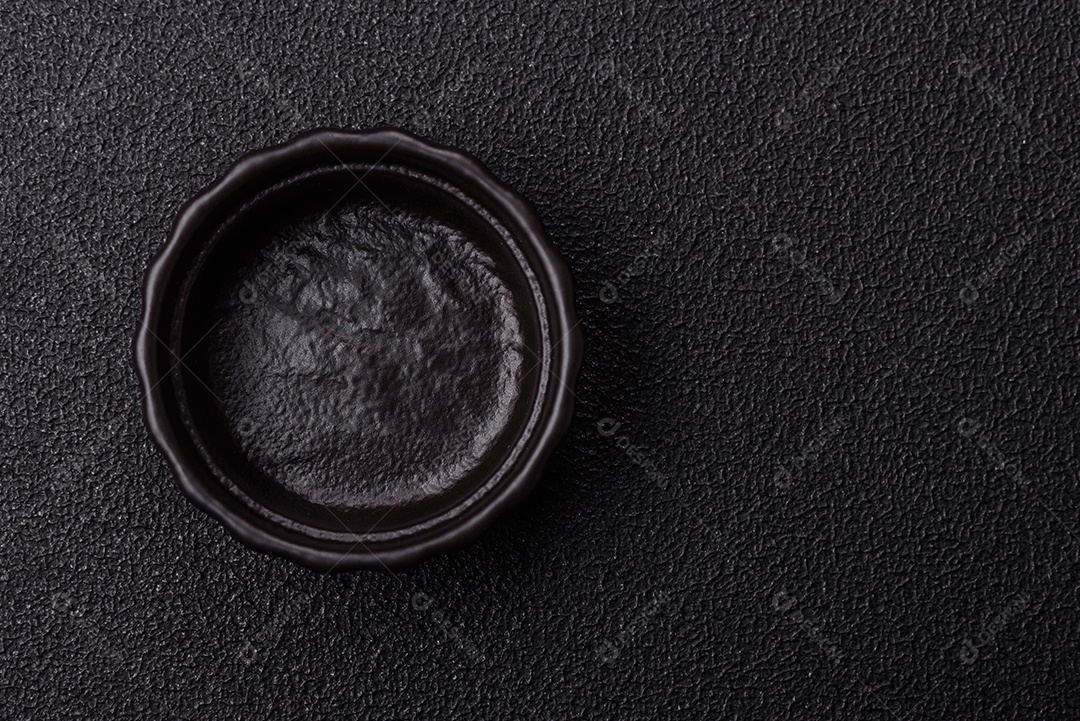 Placa redonda de cerâmica vazia em fundo de concreto texturizado escuro. Talheres, preparação para o jantar