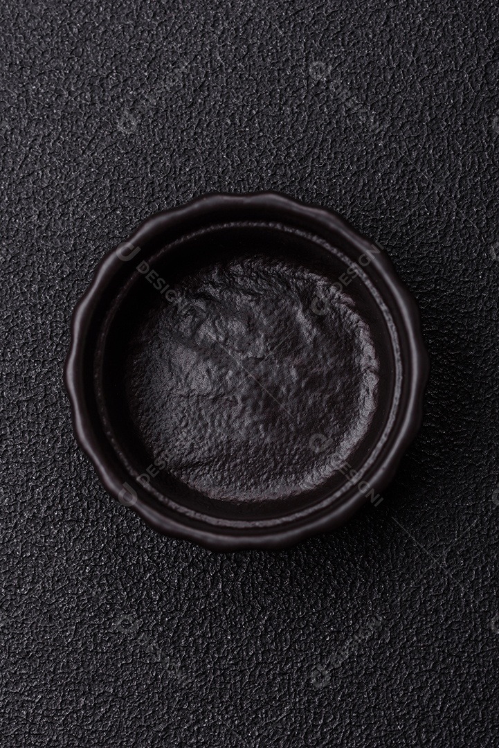 Placa redonda de cerâmica vazia em fundo de concreto texturizado escuro. Talheres, preparação para o jantar