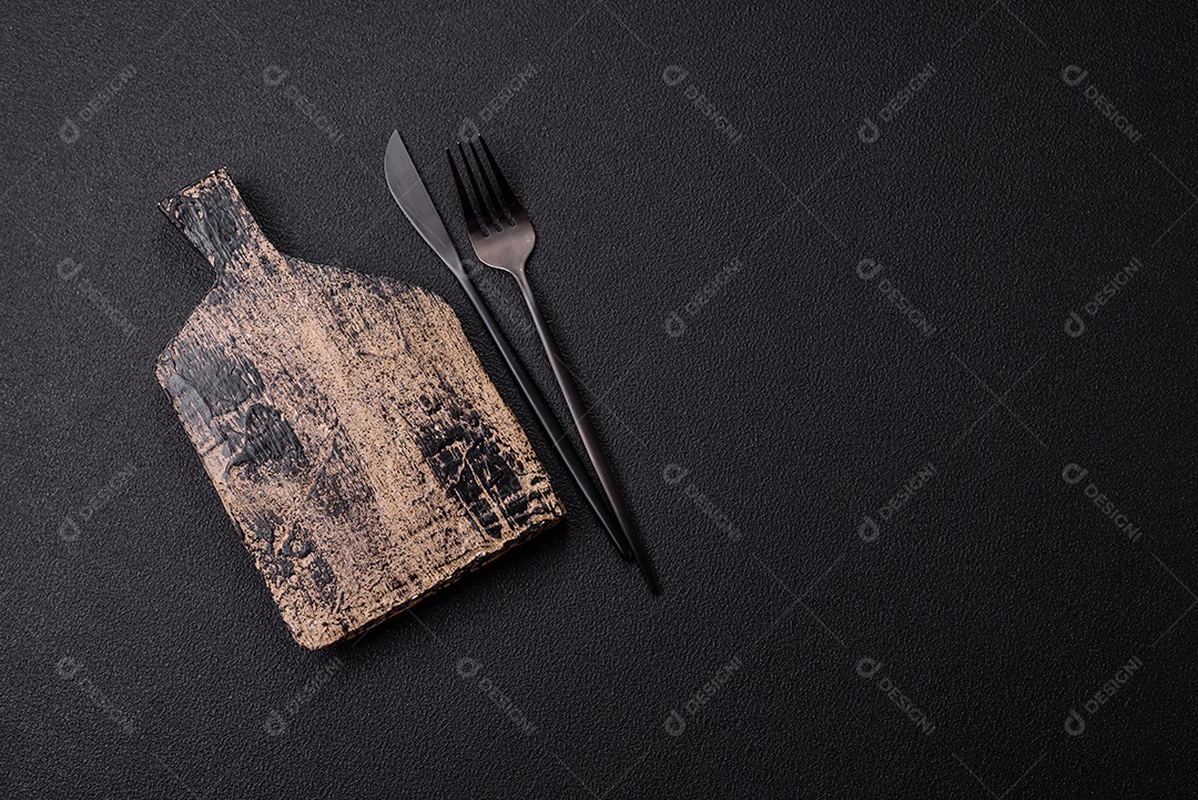 Tábua de corte de madeira vazia em fundo de concreto texturizado escuro. Talheres, preparação para o jantar