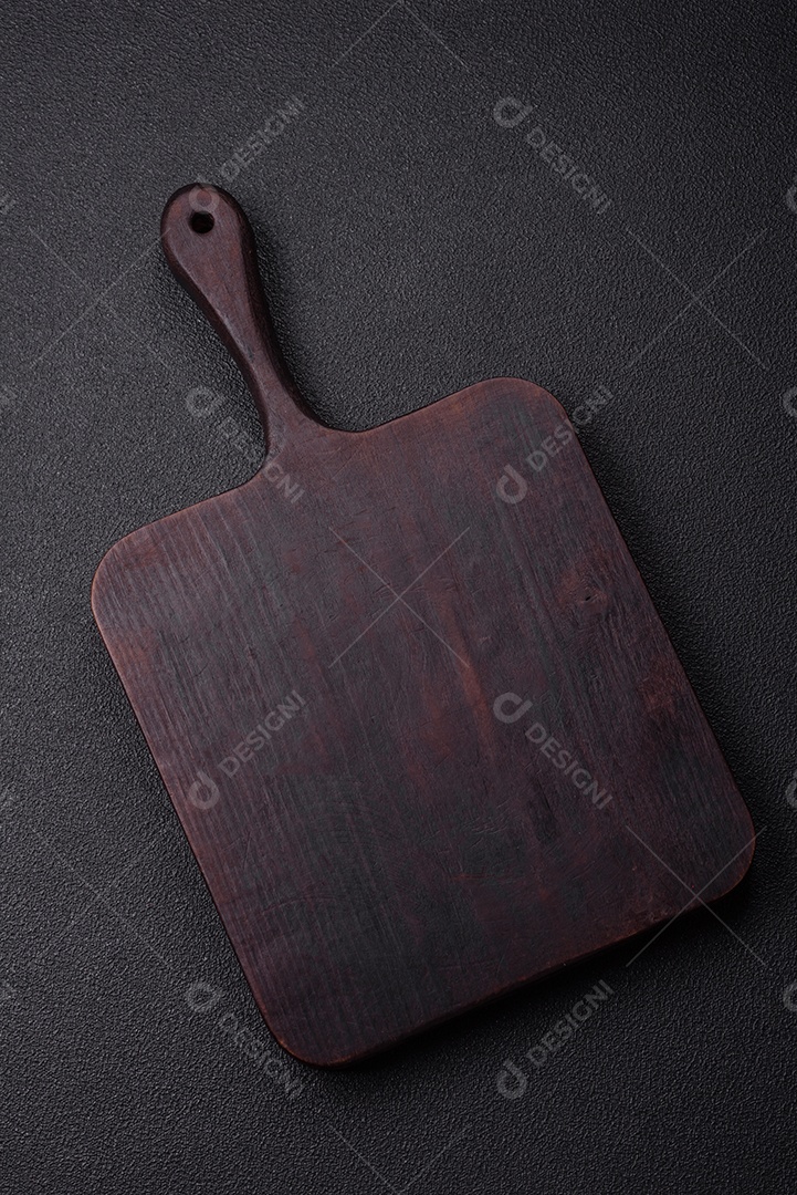 Tábua de corte de madeira vazia em fundo de concreto texturizado escuro. Talheres, preparação para o jantar