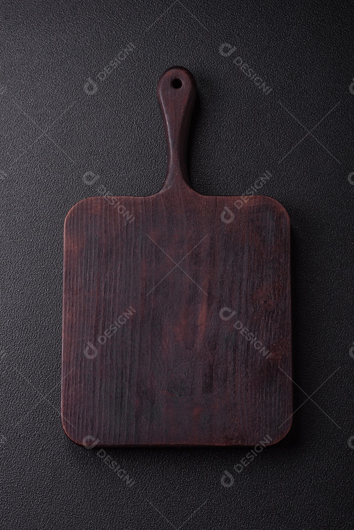 Tábua de corte de madeira vazia em fundo de concreto texturizado escuro. Talheres, preparação para o jantar