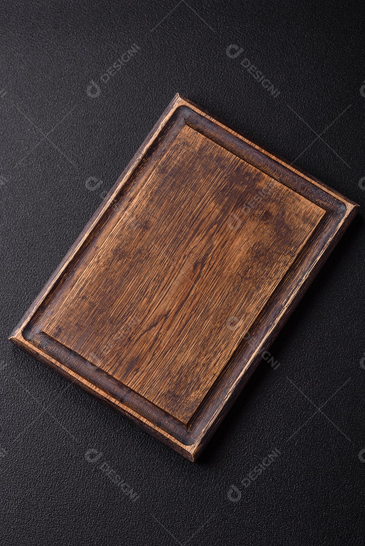 Tábua de corte de madeira vazia em fundo de concreto texturizado escuro. Talheres, preparação para o jantar