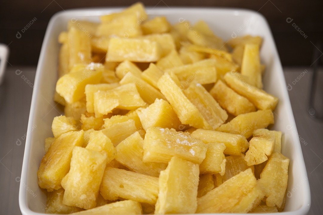 Mandioca frita sobre tigela em uma mesa branca