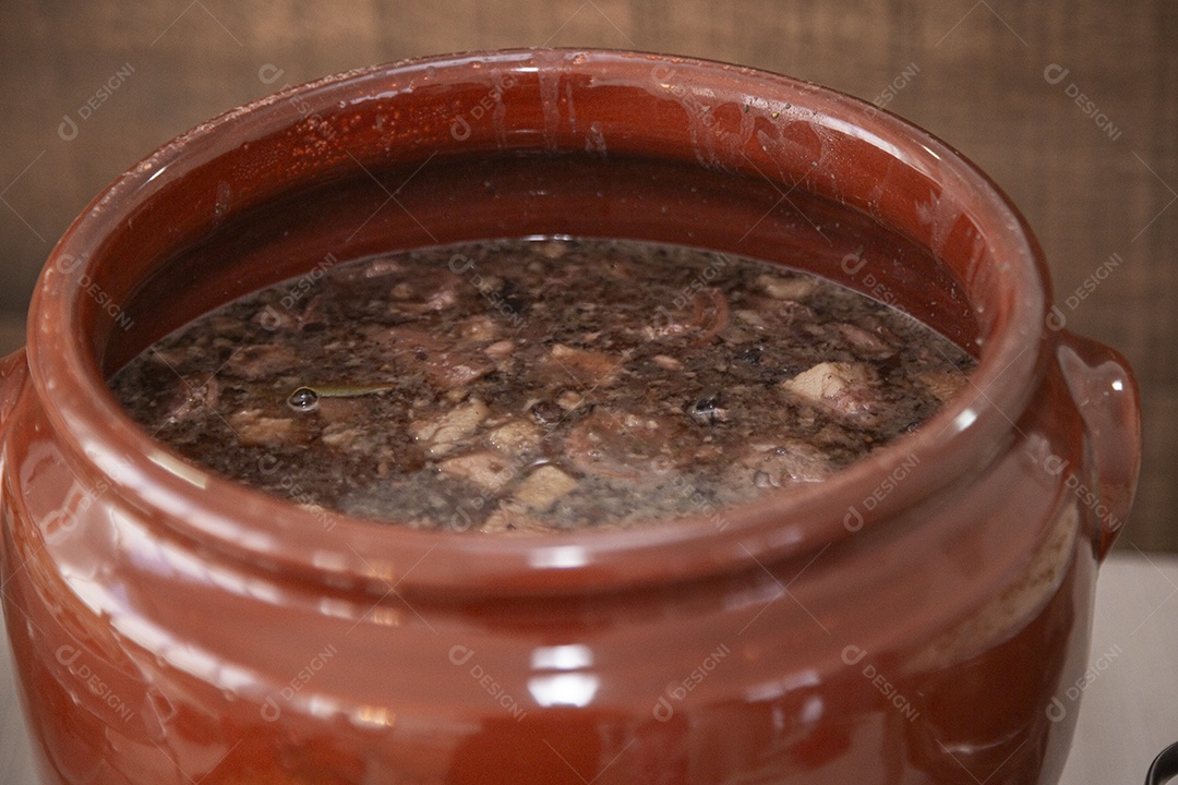 Feijoada sobre panela vermelha sobre fogão