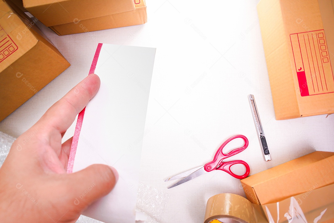 Conta branca em branco em uma mão com caixas de mercadorias para embalagem