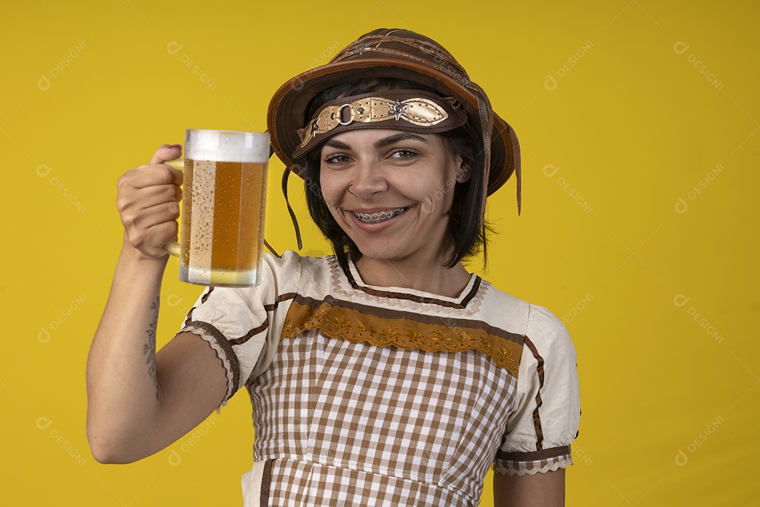 Jovem vestindo fantasia típica de festa junina segurando uma caneca de cerveja gelada