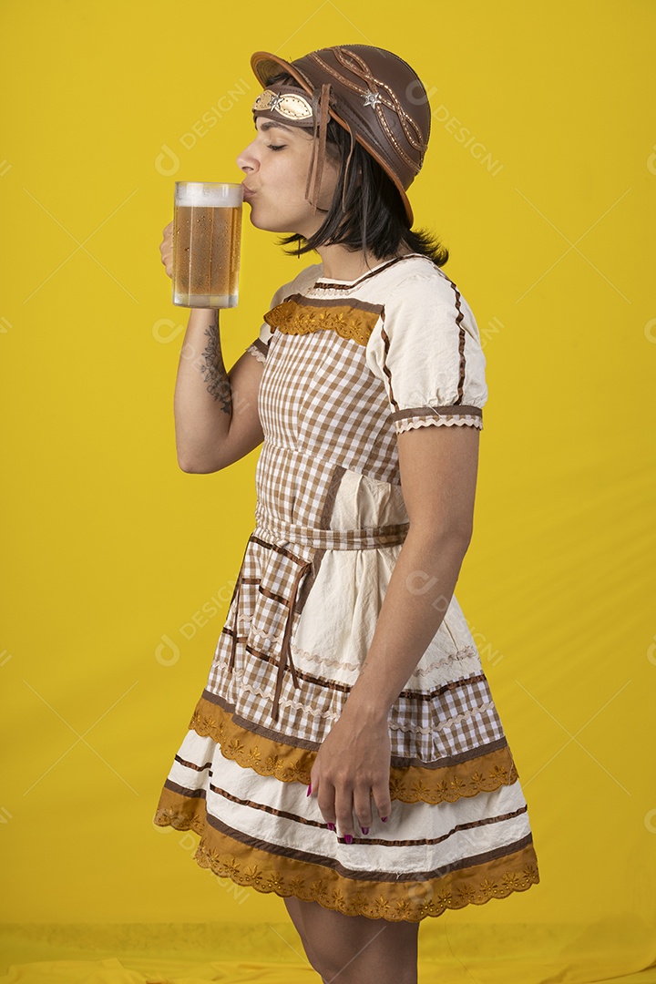 Jovem vestindo fantasia típica de festa junina bebendo uma caneca de cerveja gelada