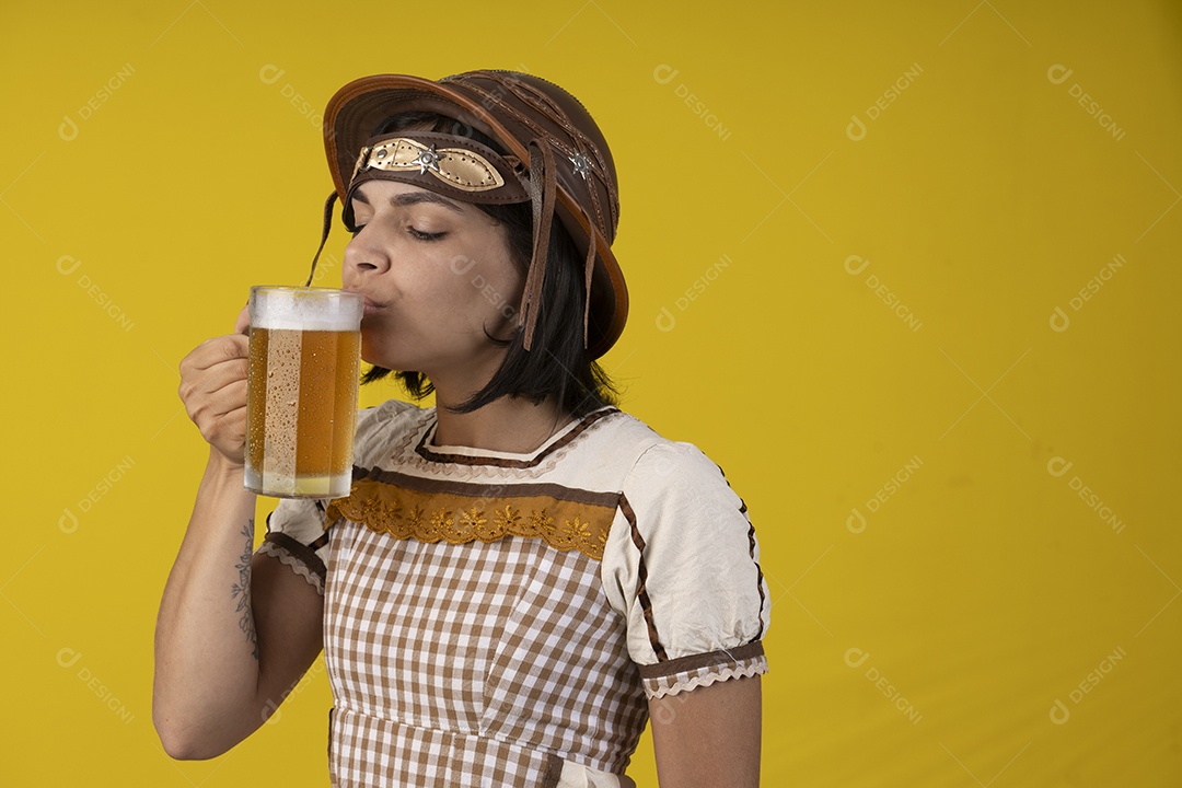 Jovem vestindo fantasia típica de festa junina bebendo uma caneca de cerveja gelada