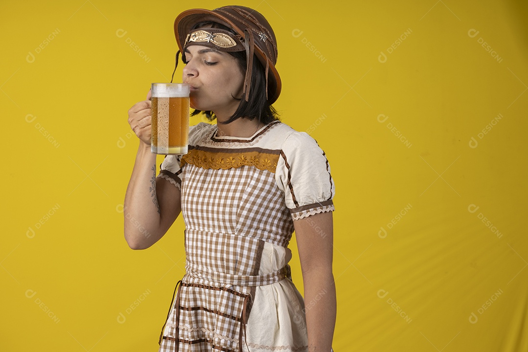 Jovem vestindo fantasia típica de festa junina bebendo uma caneca de cerveja gelada