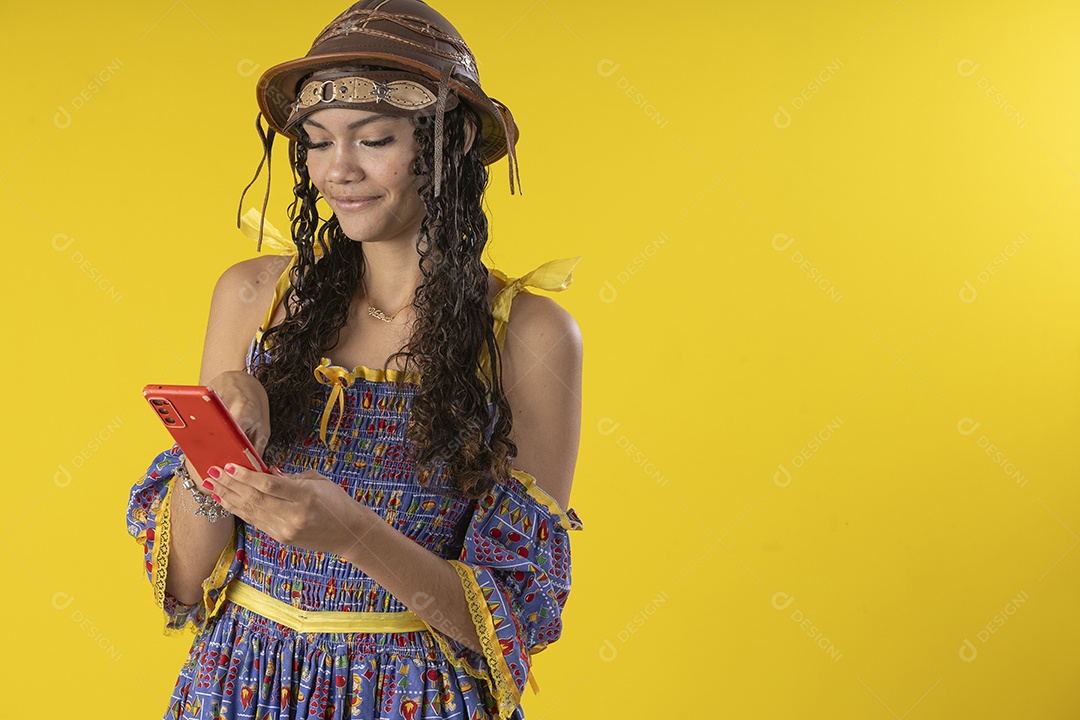 Uma menina com trajes nordestino com celular na mão