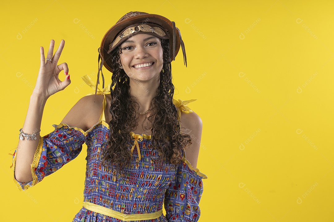 Jovem sorrindo usando chapéu de couro típico de festa junina com gesto de ok