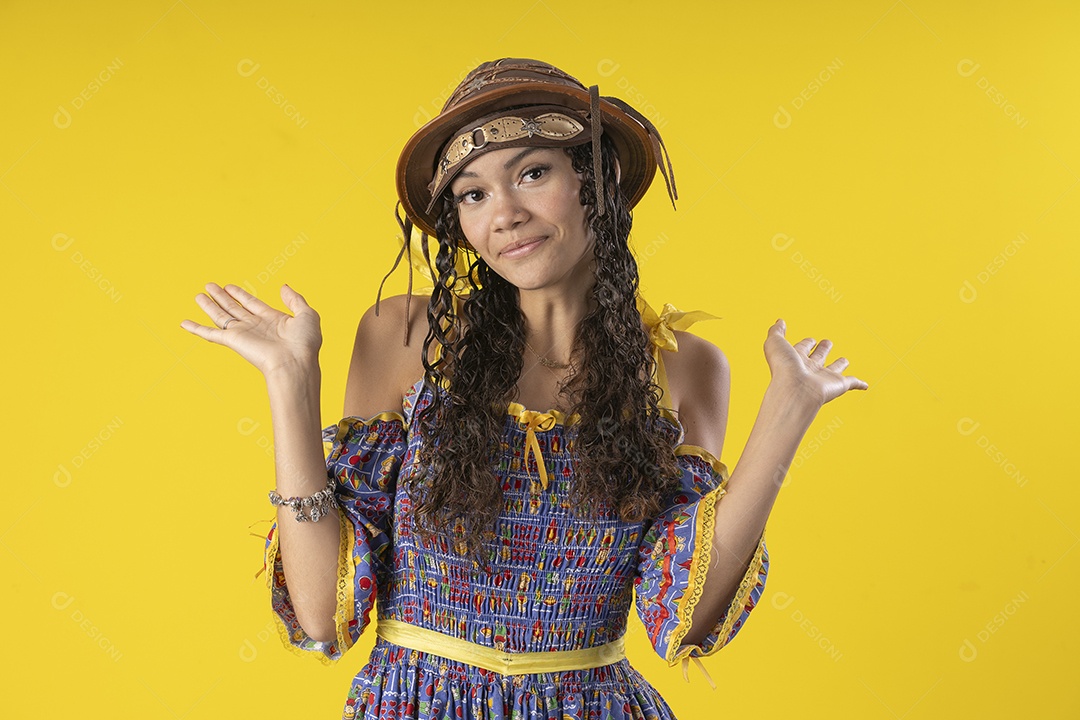 Jovem com trajes juninos e chapéu de couro com mãos para cima