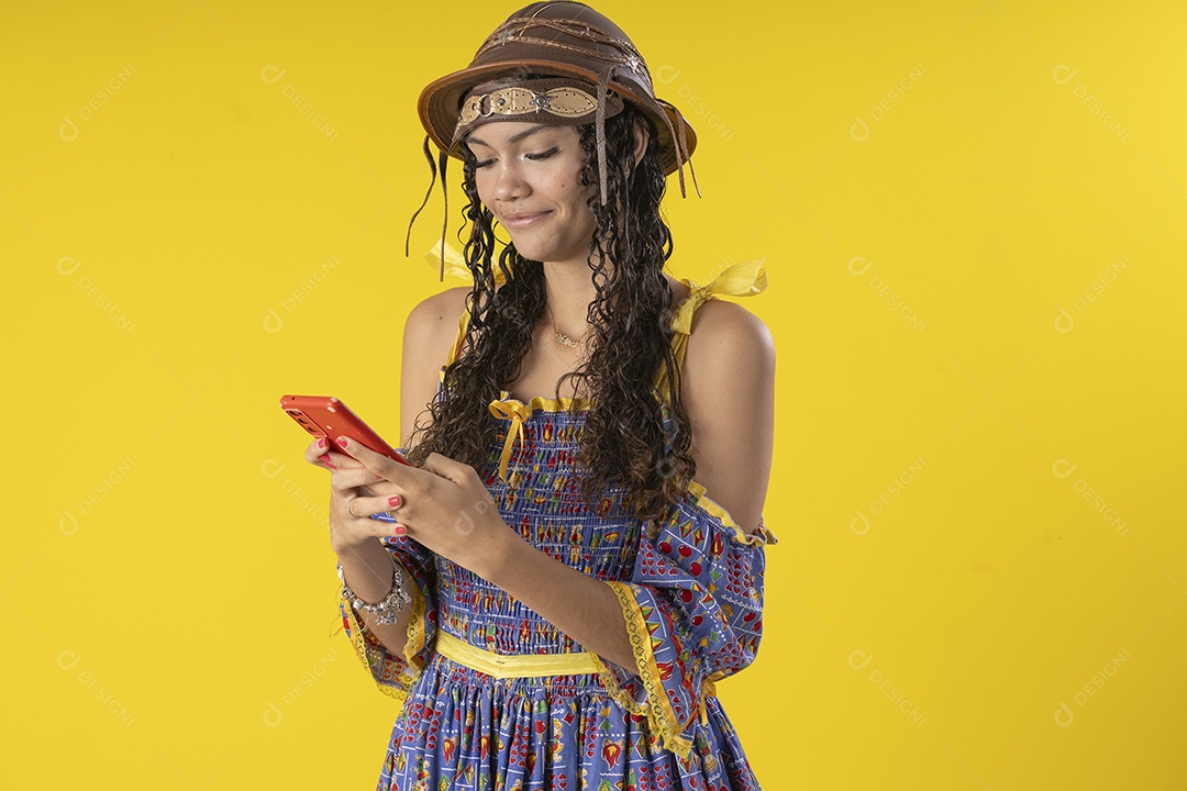 Jovem vestindo fantasia típica de festa junina segurando celular na mão