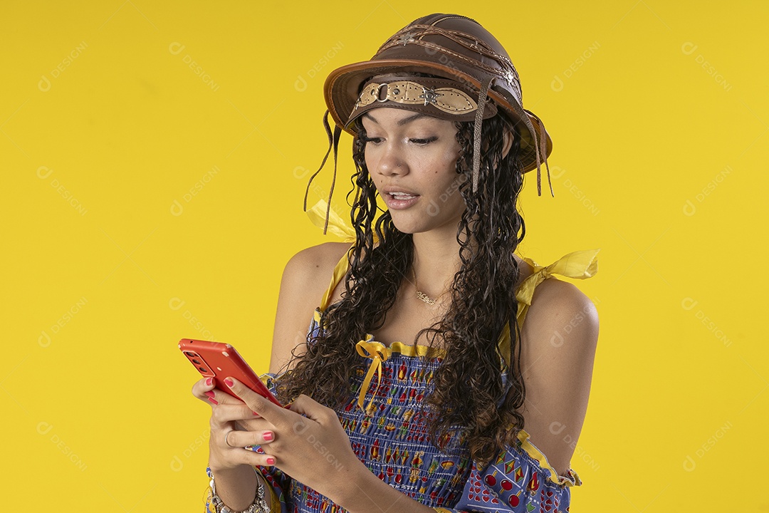 Jovem vestindo fantasia típica de festa junina segurando celular na mão