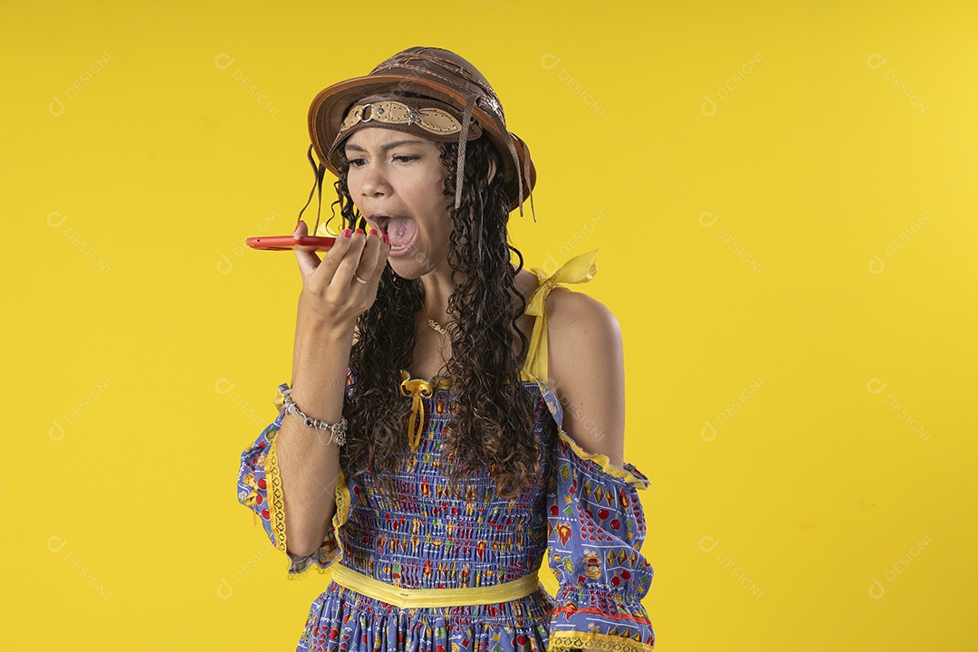 Jovem gritando no celular com alguém e trajes de festa junina
