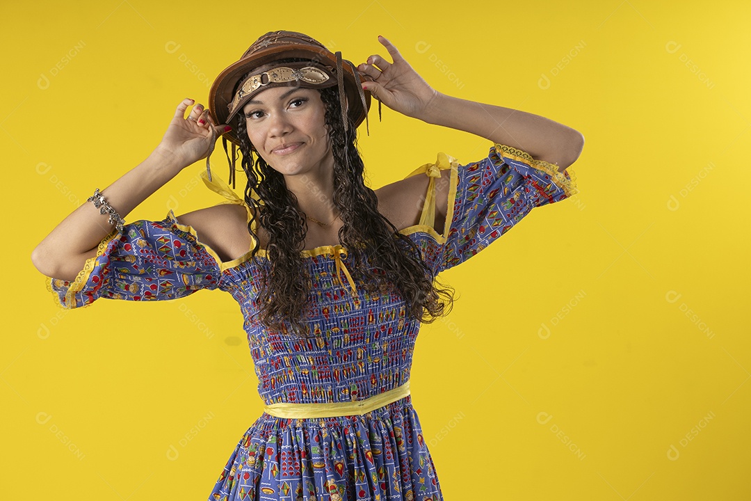 Jovem vestindo fantasia de festa junina pegando no chapéu de couro