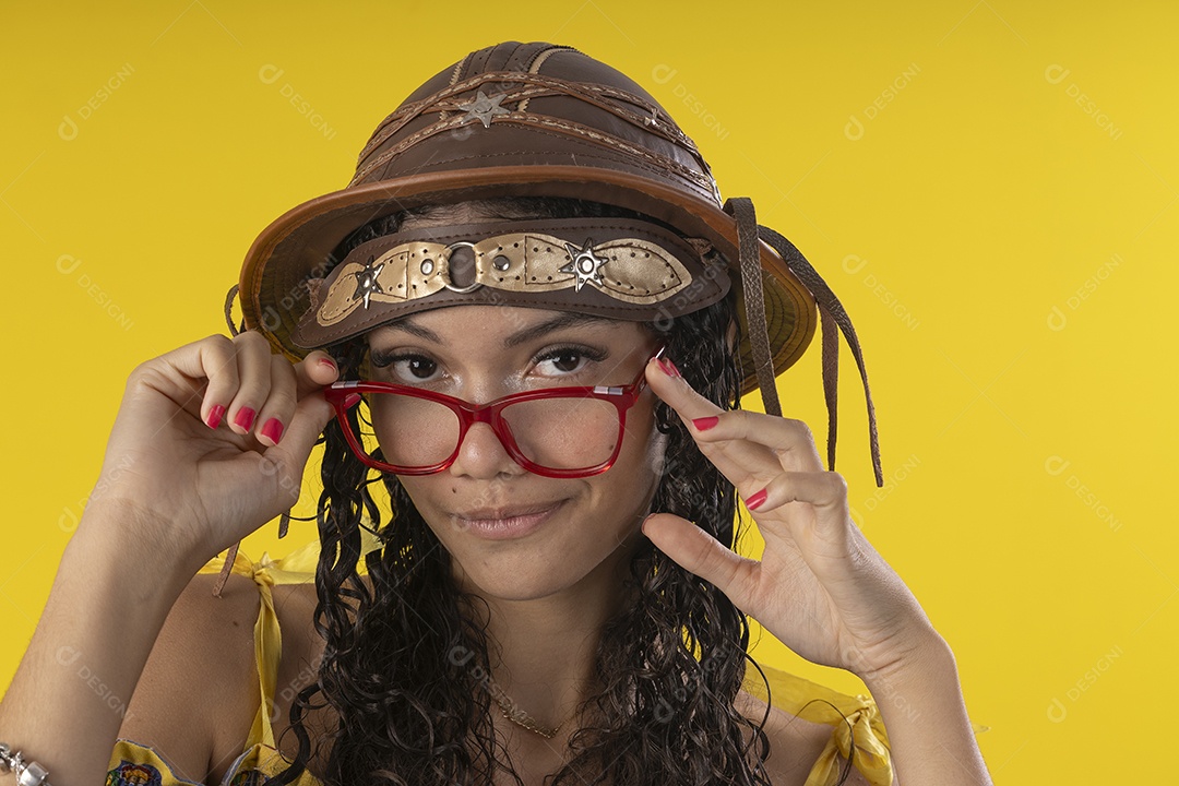 Jovem usando óculos e chapéu de couro típico de festa junina
