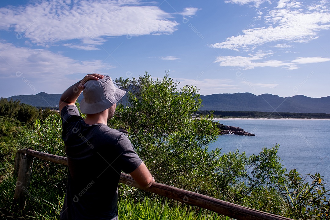 Homem com chapéu nas costas olhando o mar