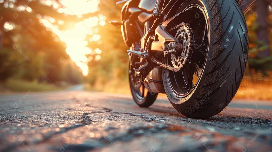 Uma motocicleta está estacionada em uma estrada molhada com um lindo pôr do sol ao fundo