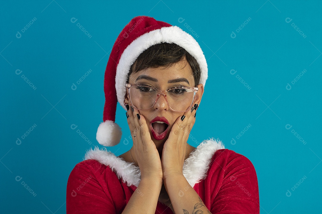 Jovem mulher com roupa de Mamãe Noel e chapéu com gesto de surpresa