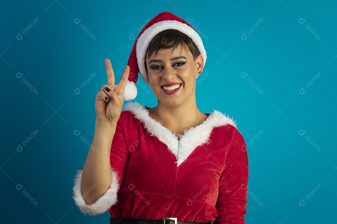 Mulher jovem com roupa de Mamãe Noel e chapéu com gesto de dois dedo