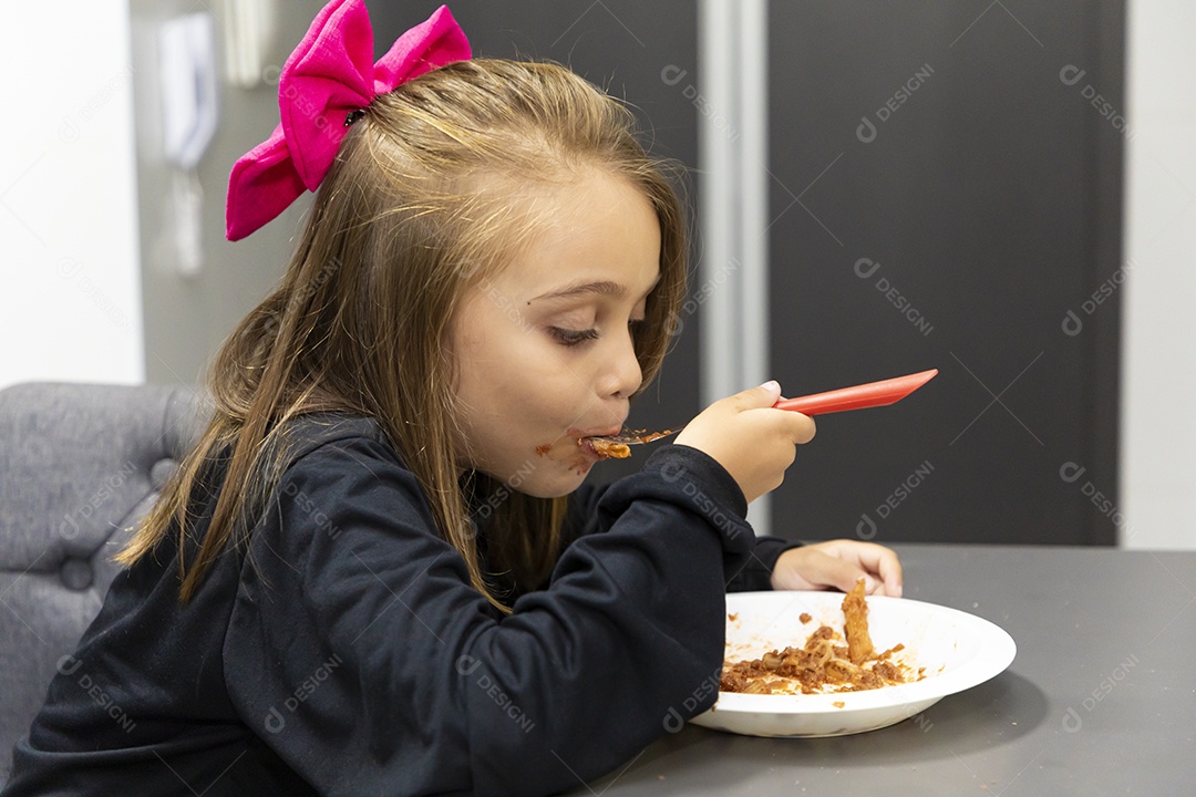 Linda garotinha sobre fundo isolado branco se alimentando