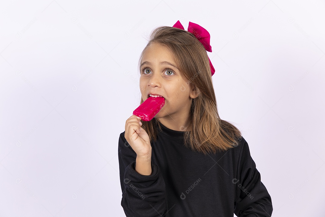Linda garotinha sobre fundo isolado branco chupando picolé