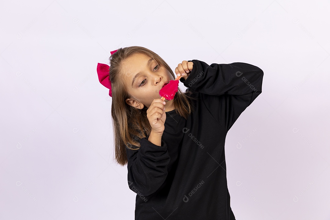 Linda garotinha sobre fundo isolado branco chupando picolé