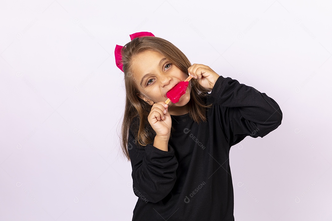 Linda garotinha sobre fundo isolado branco chupando picolé