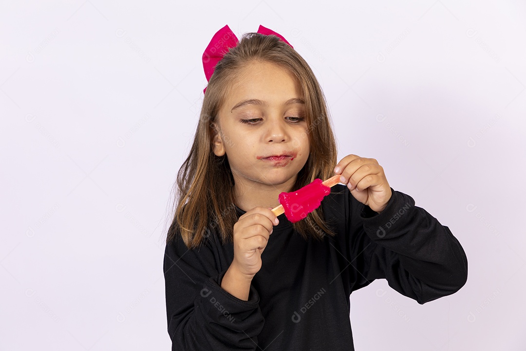 Linda garotinha sobre fundo isolado branco chupando picolé