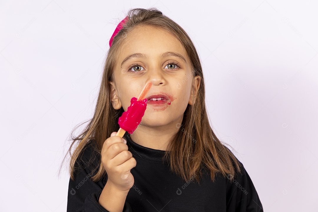 Linda garotinha sobre fundo isolado branco chupando picolé