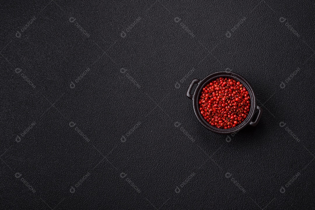 Especiarias, ervilhas de pimenta da Jamaica na cor vermelha ou rosa em uma tigela sobre um fundo preto de concreto. Cozinha asiática