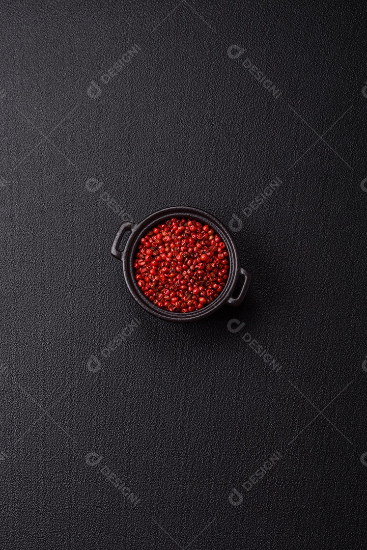 Especiarias, ervilhas de pimenta da Jamaica na cor vermelha ou rosa em uma tigela sobre um fundo preto de concreto. Cozinha asiática