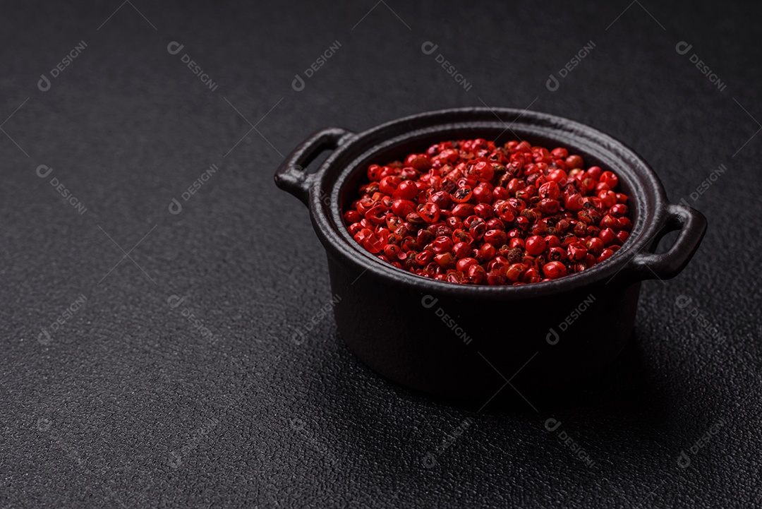 Especiarias, ervilhas de pimenta da Jamaica na cor vermelha ou rosa em uma tigela sobre um fundo preto de concreto. Cozinha asiática