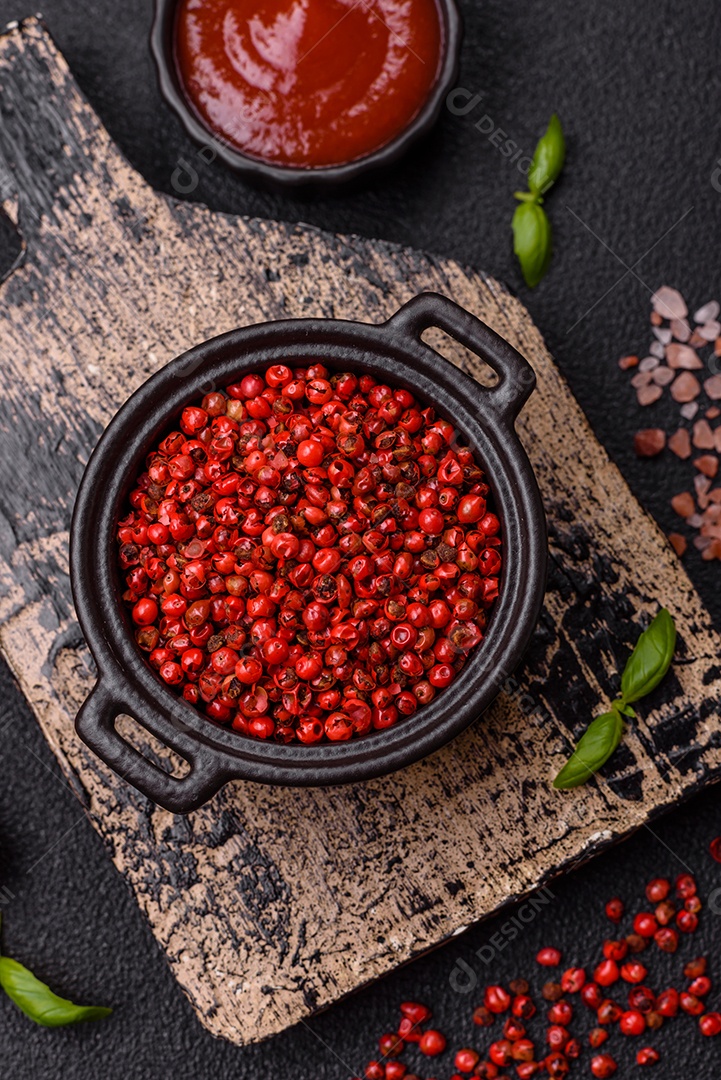 Especiarias, ervilhas de pimenta da Jamaica na cor vermelha ou rosa em uma tigela sobre um fundo preto de concreto. Cozinha asiática